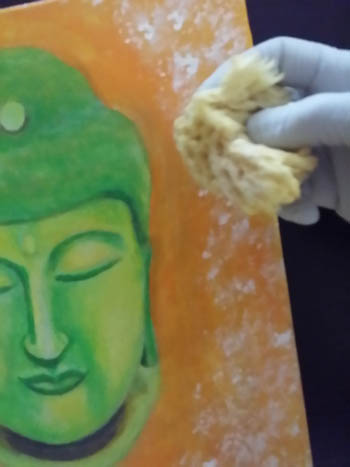 I'm using a small sponge to create texture around this painting of Buddha I'm working on.